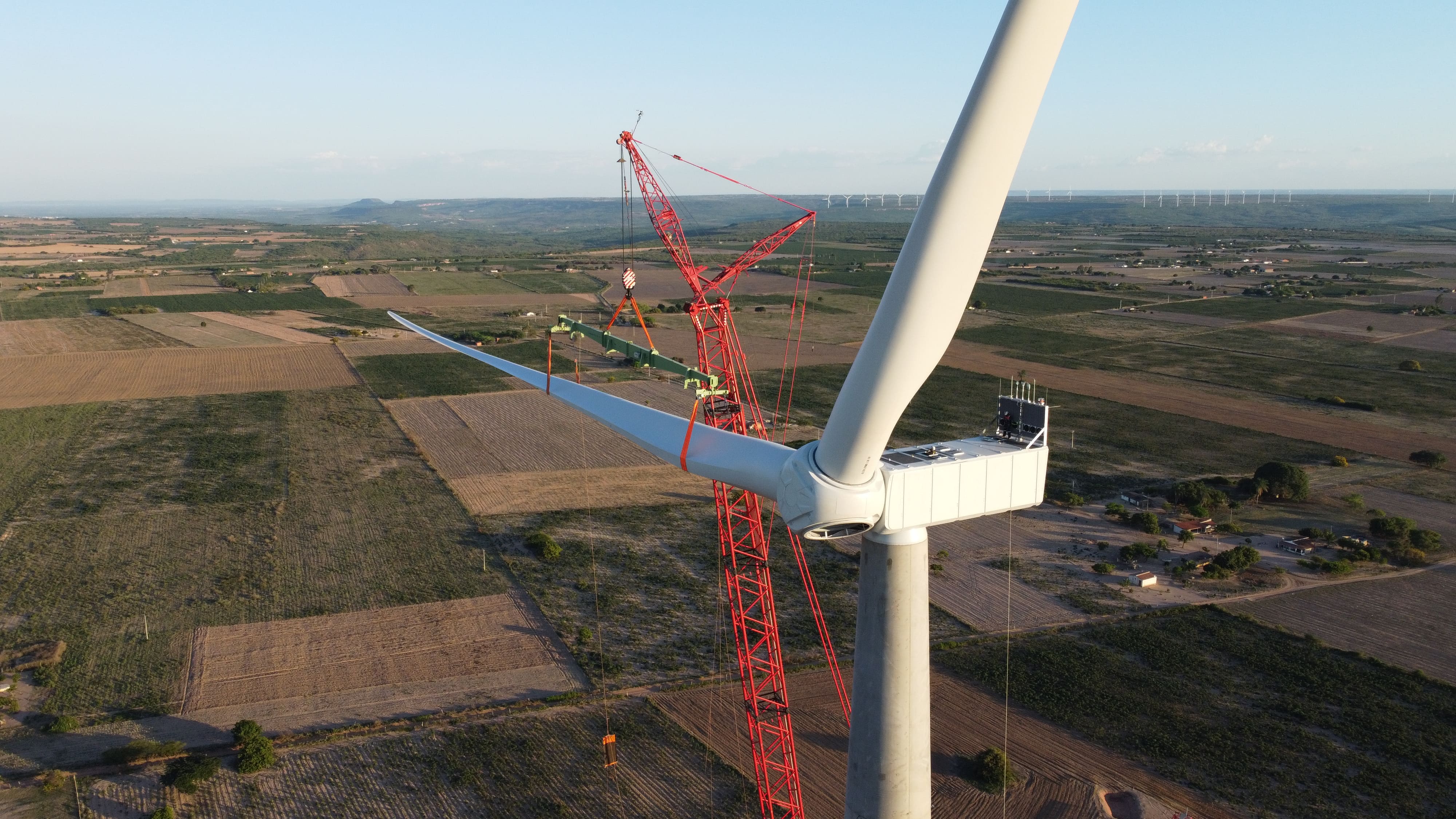 a large crane in a field with Millau Viaduct in the background