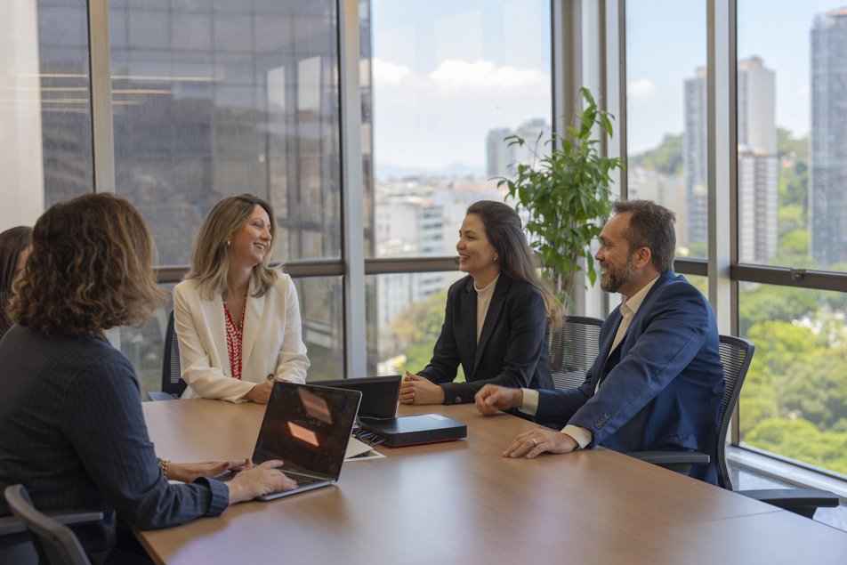 a group of people sitting around a table with laptops